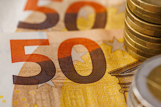 Close-up macro of fifty euro banknotes with stacked euro coins, shallow depth of field, finance, savings, inflation and European economy concept