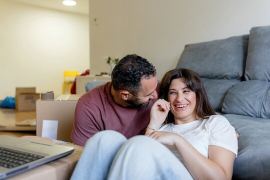 Happy couple relax on sofa among moving boxes at home