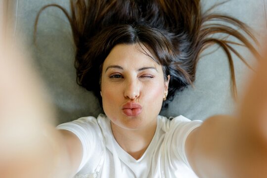 Woman take playful selfie with kiss face from above