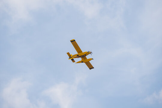 Firefighting seaplane flying overhead against cloudy sky