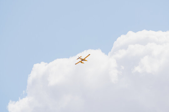Firefighting seaplane flying overhead against cloudy sky