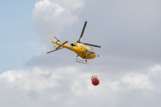 Firefighting helicopter release water drop over wildfire zone