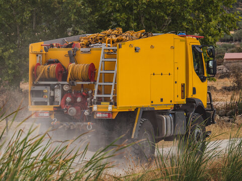 Yellow firefighting truck on dusty forest wildfire terrain