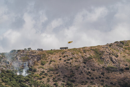 Firefighting aircraft combat wildfire over rocky forest hill