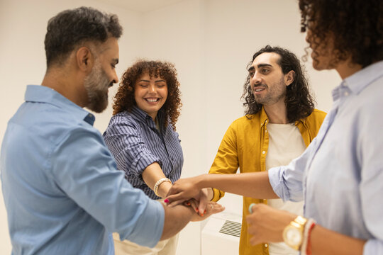 Coworking office team unite hands in workplace huddle