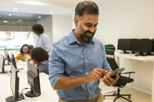 Smiling businessman use smartphone in coworking office