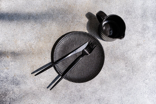 Black tableware and cutlery on a textured dinner table