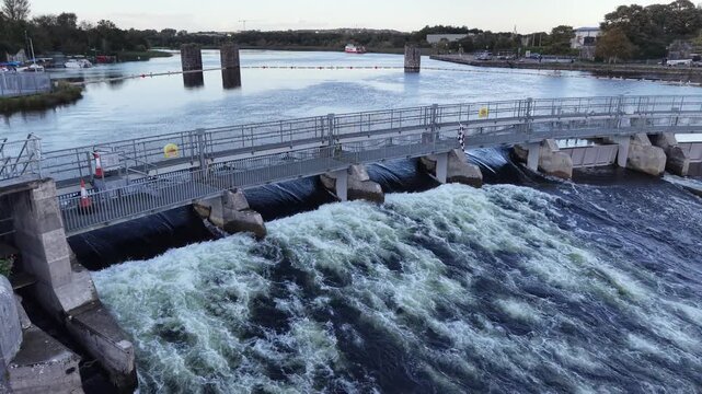 Rushing water flows through the gates of Salmon Weir on the River Corrib in Galway City Ireland.