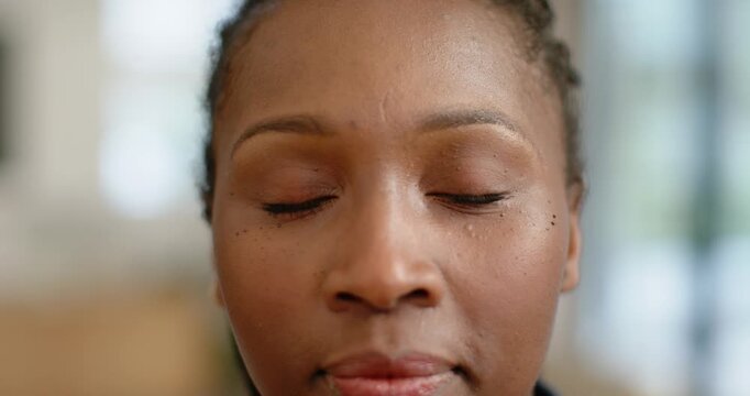 African woman breathing, eyelids fluttering then opening, grinning at home with freckles