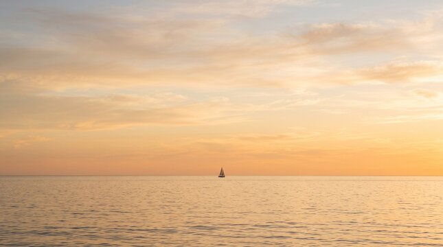 Minimalist seascape at sunset featuring a solitary sailboat sailing on a calm golden ocean under a soft hazy sky with warm pastel colors conveying tranquility and peace in a nature landscape