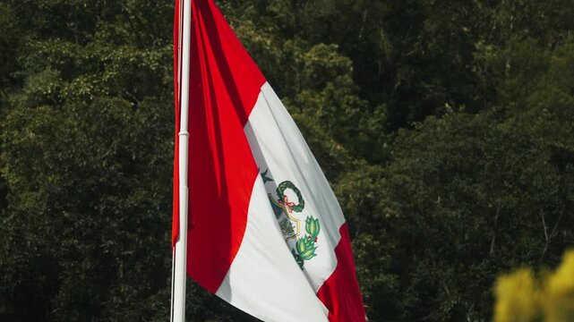 Cinematic close-up of the red and white national flag of Peru waving against the Andean landscape