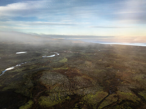 Aerial view of the scenery over a mountain range with clouds and fog - Iceland