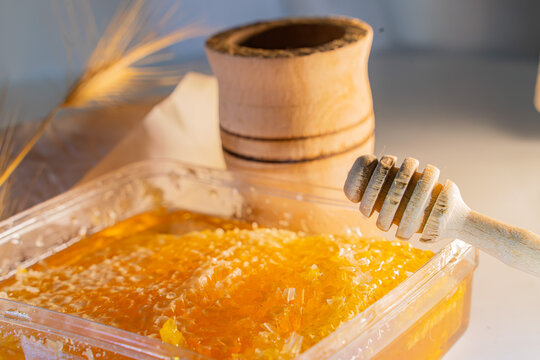 Fresh Honeycomb in Container with Wooden Dipper, Mortar and Wheat