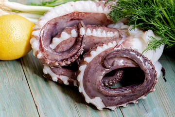 Large octopus tentacles with vegetables on a wooden table close-up © TETYANA