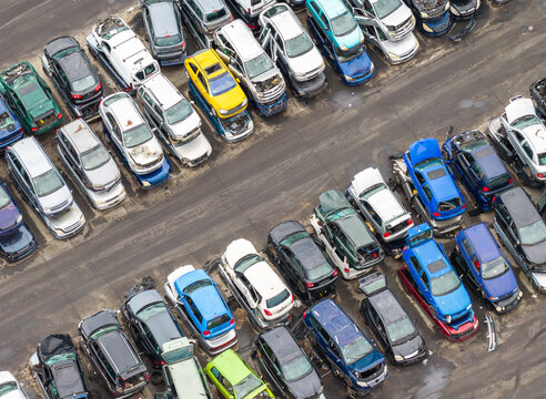 Aerial view of an end of life vehicle recycling facility with rows of salvaged cars in various colors parked on asphalt in Gdansk, Pomeranian Voivodeshi, Poland.