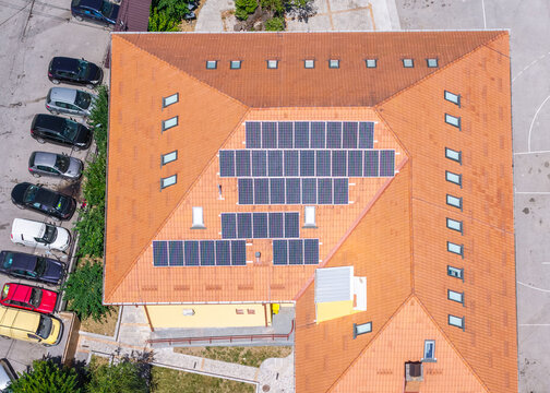 Aerial view of Vevchani featuring a building roof covered with solar panels and cars parked in the adjacent lot in Vevchani, Vevcani Municipality, North Macedonia.