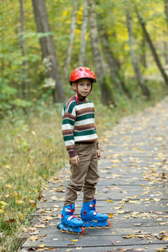 Cute school child, boy, riding roller skates, skating on the street autumn