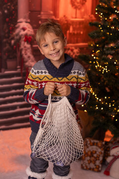 Little child, preschool boy, sending letter to santa in christmas mailbox, christmas decoration around him, outdoor snow shot