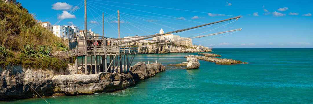 Vieste Gargano Puglia Italy hig hresolution panortama. View of trabucco wooden platform reveal of historic white town on rocky cliff. Authentic traditional fishing net