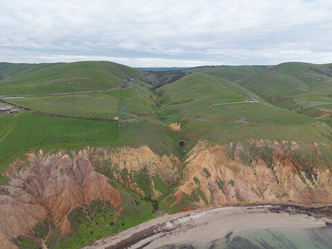 Aerial view of green hills and a deep gully above a South Australian beach