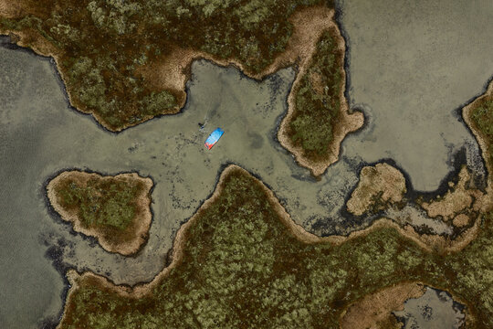 Aerial view of Hlidarvatn with a kite surfer gliding over the shallow lake waters surrounded by mossy volcanic terrain in Sveitarfelagid Olfus, Iceland.