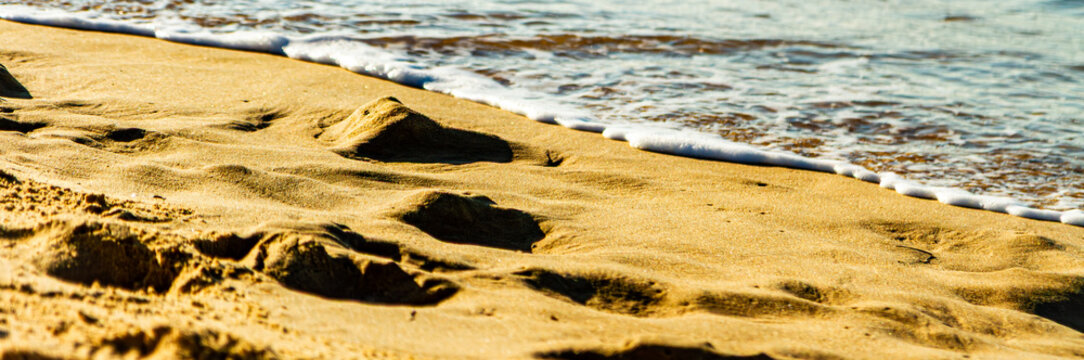 Traces de pas sur une plage se faisant effacer par les vagues de l'oc&eacute;an