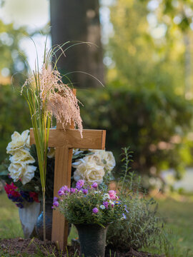 Helles Holzkreuz mit Blumen und Gr&auml;sern am Grab nach der Beisetzung auf dem Park Friedhof