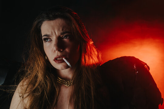A young woman smokes a cigarette in dramatic red back lighting, looking pensive. Moody portrait with cinematic lighting and visible smoke accentuating her intense expression.