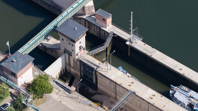 Aerial view of the Neckar-Staustufe und Schleuse Rockenau, showing concrete lock chambers, control towers, and a boat on the Neckar River in Eberbach, Baden-Wurttemberg, Germany.