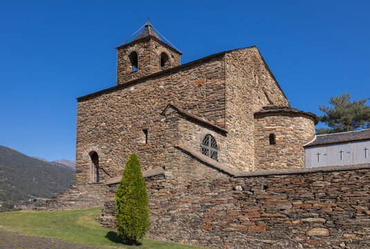 Ancient stone Church of Sant Cristofol in La Massana, Andorra, showcasing Romanesque architecture with bell tower, apse and stone walls against clear blue sky