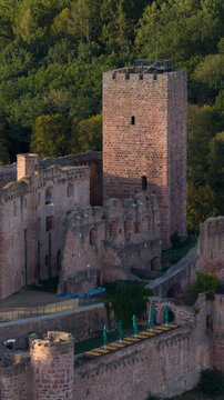 Aerial view of the historic Henneburg castle ruins with its prominent red sandstone tower, stone walls, and surrounding lush forest in Stadtprozelten, Bayern, Germany.