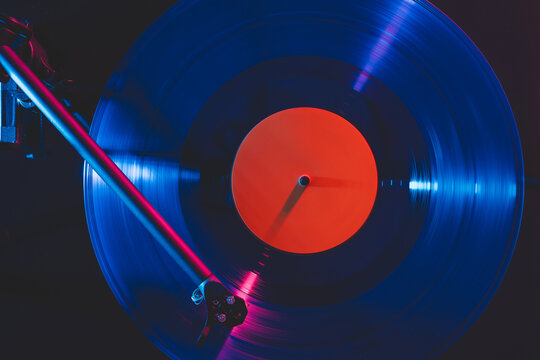 Vinyl record playing on turntable in neon light