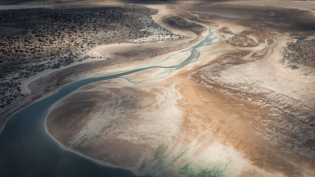 Aerial view of abstract patterns of blue water and brown sands along the coastline in Useless Loop, Western Australia, Australia.