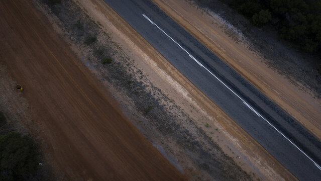 Aerial view of a paved road running parallel to a dirt track through the arid landscape of Western Australia, Perth, Western Australia, Australia.