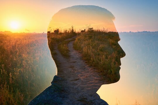 Man silhouette with a creative double exposure of a golden sunset path through a nature field