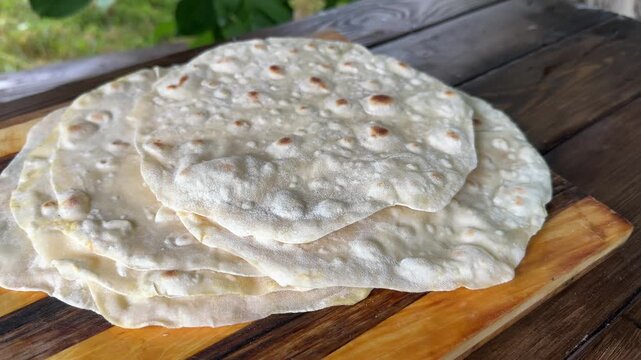 A close-up of a stack of freshly baked lavash breads on a wooden board. High quality 4k footage
