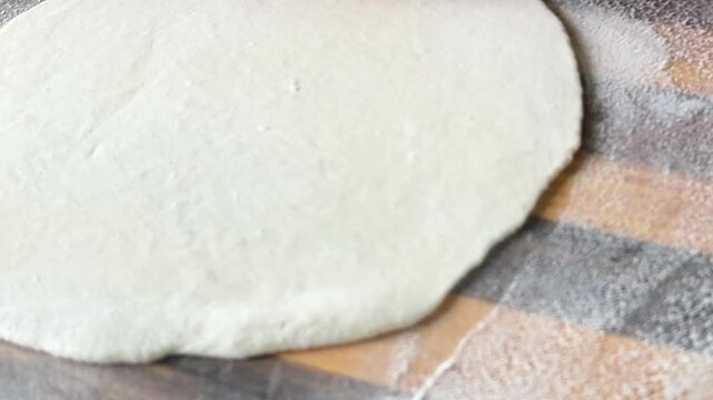 Close-up: a rolling pin rolling out lavash dough on a wooden board. High quality 4k footage