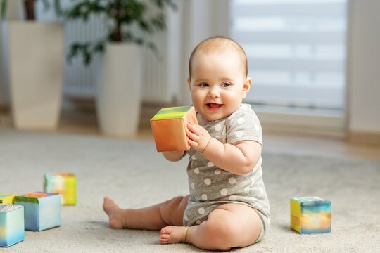 Happy baby holding colorful building block indoors