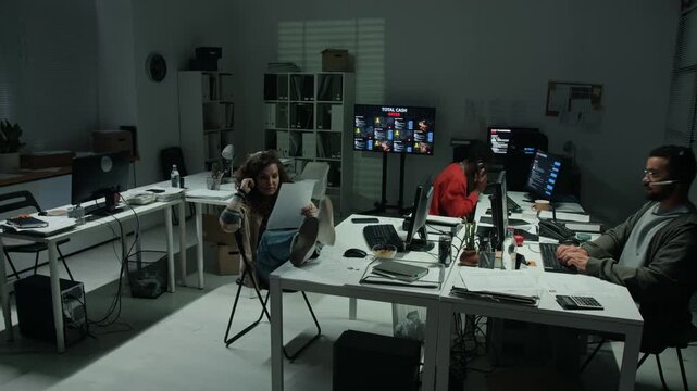 Diverse young hackers working late at computer desks in scam open space office, time lapse. Clip fits cybercrime and scam awareness campaigns