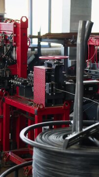 Steel wire feeding from a coil into a mesh welding machine at a wire mesh factory