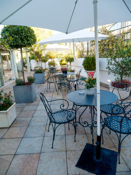 Terrasse am&eacute;nag&eacute;e avec tables, chaises en m&eacute;tal, parasols et plantes pour une r&eacute;ception &eacute;v&eacute;nementielle en ext&eacute;rieur