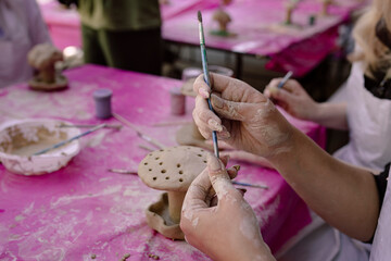 Woman holding a paintbrush while decorating a handmade clay mushroom. © sav_an_dreas
