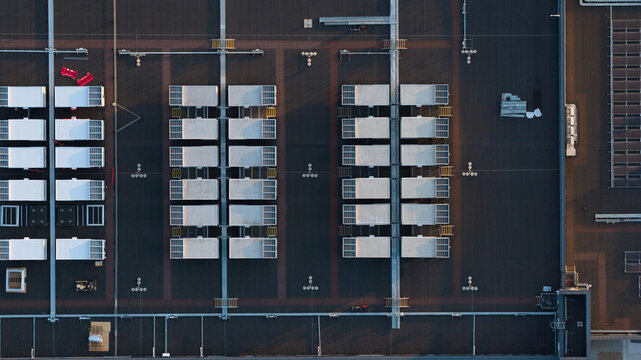 Aerial view of a flat industrial building roof featuring rows of HVAC units and solar panels arranged in a grid pattern in Bracknell, England, United Kingdom.