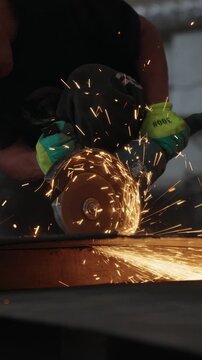 Worker cutting a steel plate with an angle grinder with sparks flying in a workshop