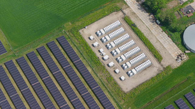 Aerial view of a solar farm with rows of photovoltaic panels and a battery energy storage system in a rural landscape in Wanneperveen, Overijssel, Netherlands.
