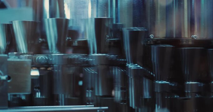 High speed conveyor transports dark medicine vials through enclosed factory section. Automated line moves containers rapidly toward next pharmaceutical stage