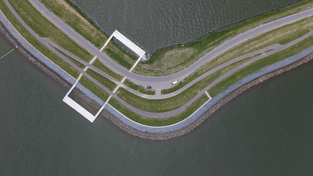 Aerial view of a modern architectural structure integrated into the dike path along the water in Uitdam, North Holland, Netherlands.