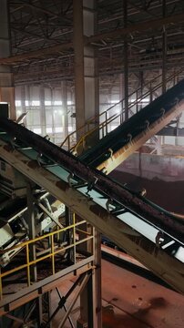 Clay moving up an inclined belt conveyor in a brick factory hall drone shot