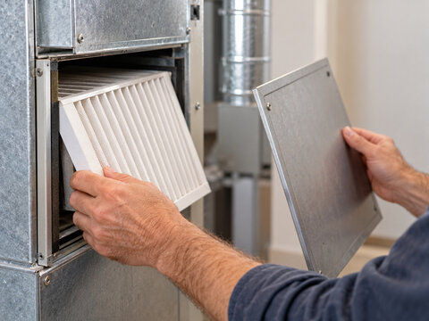 Hands changing air filter in a home heating system  