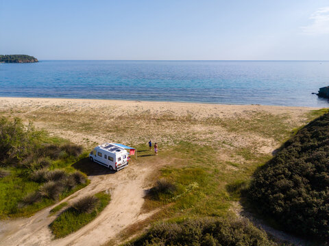In the tranquil setting of Paralia Azapiko beach, two travelers camping in a camper van explore the golden sands and crystal-clear waters of Neos Marmaras, Central Macedonia, Greece.